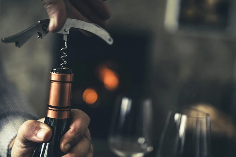 A man using an entire bottle opener on a cork