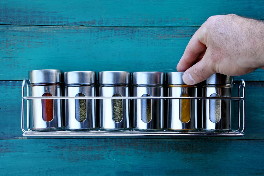 A person placing spices on a spice rack