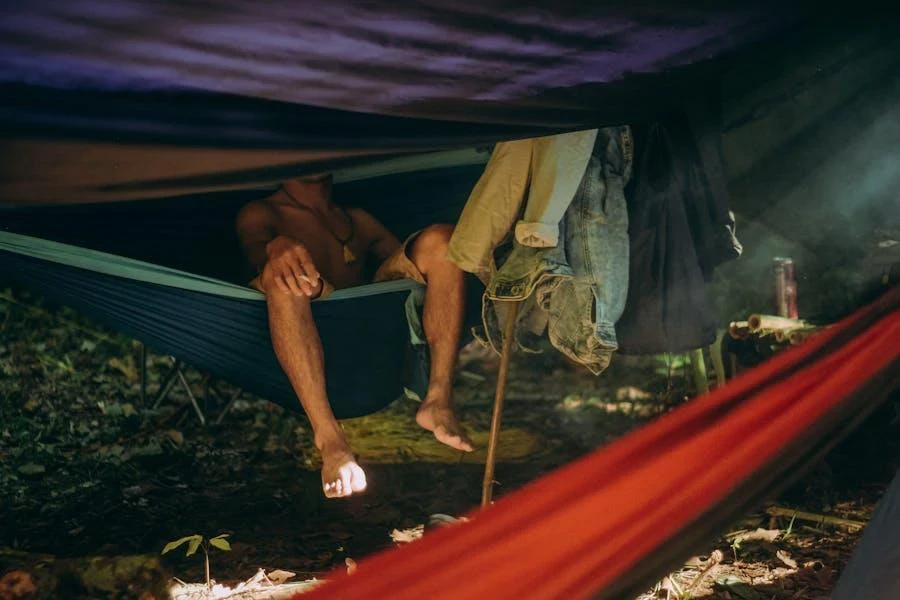 A person resting on a hammock in the woods