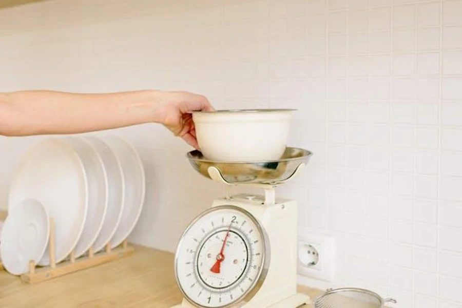 A person weighing something with a mechanical kitchen scale