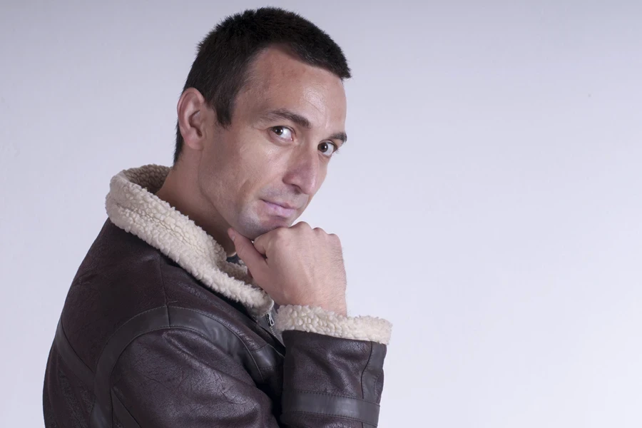 A young man posing in a shearling-lined coat