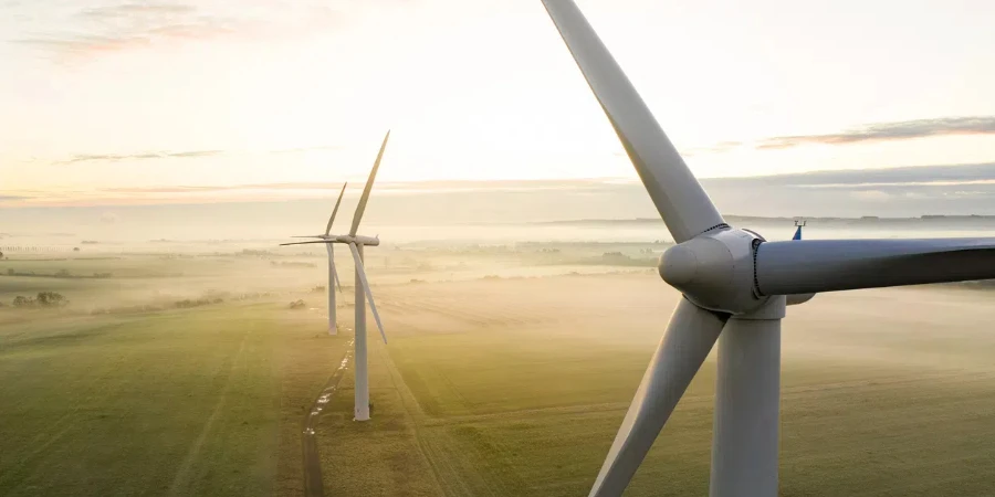 Aerial view of three wind turbines in the early morning fog at sunrise in the English countryside