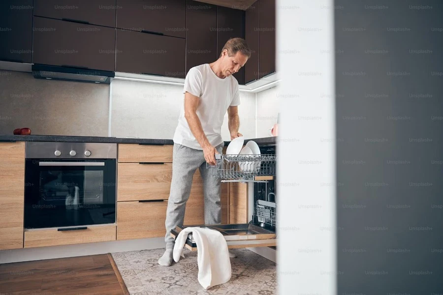 An adult male putting dishes inside a dishwasher