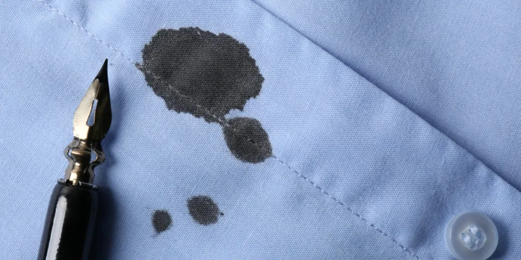 Black ink stain on light blue shirt and pen