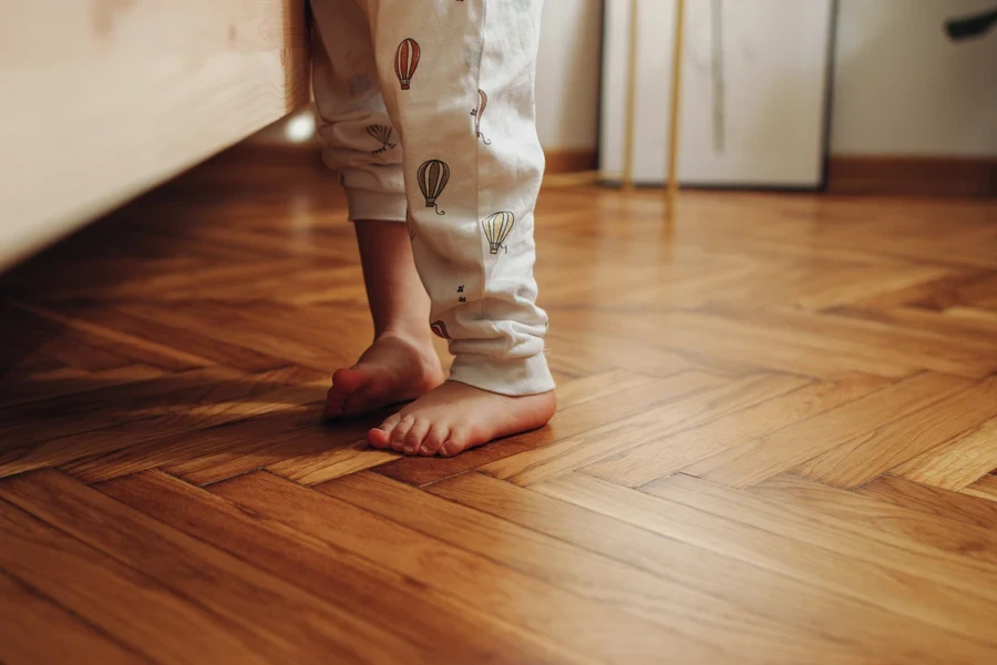 Child standing on a herringbone pattern parquet