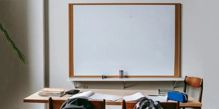 Classroom with whiteboard and desk with stationery