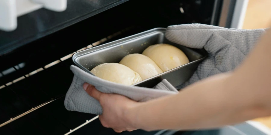 Close up of Womans Hands Putting Buns into an Oven