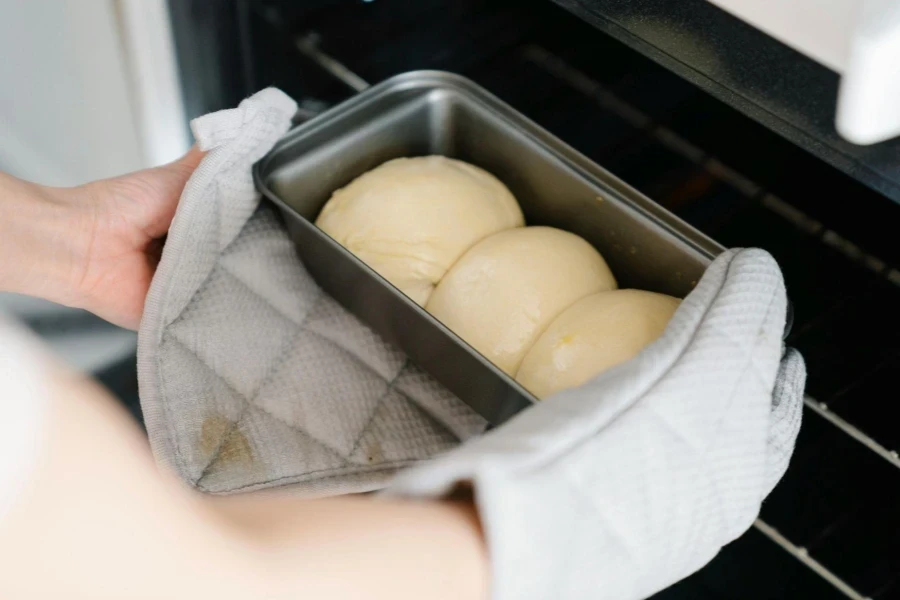 Close up of Womans Hands Putting Buns into an Oven