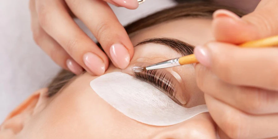 Make-up artist makes the procedure of lamination and dyeing of eyelashes to a beautiful woman in a beauty salon. Eyelash extensions. Eyelashes close-up