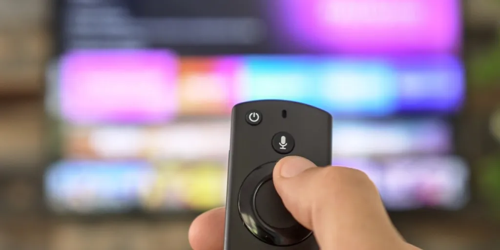 Male hand holding the TV remote control and changing TV channels