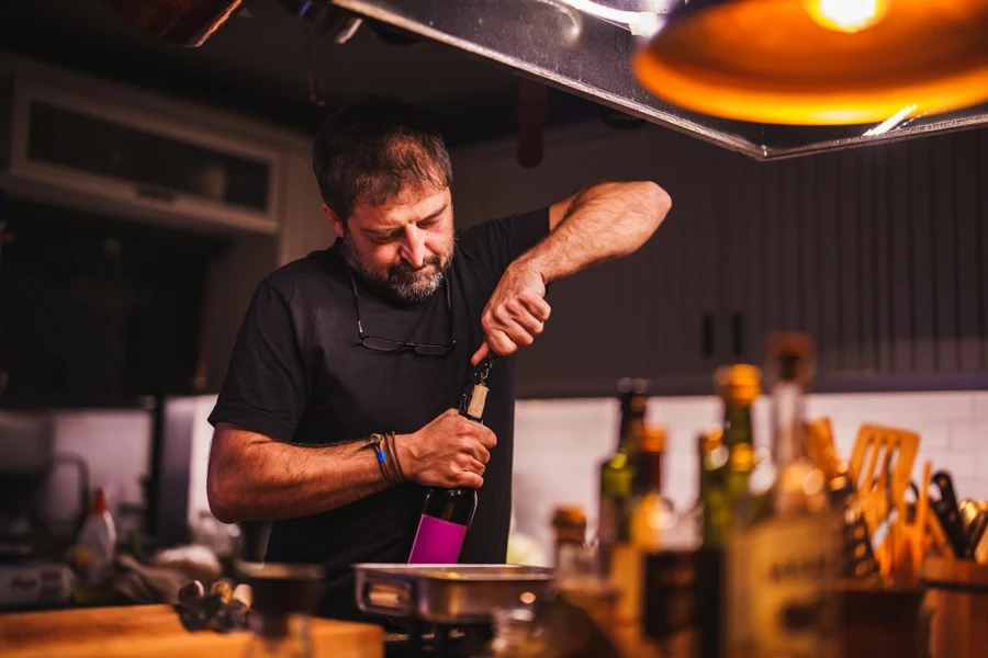 Man opening a wine bottle with a corkscrew