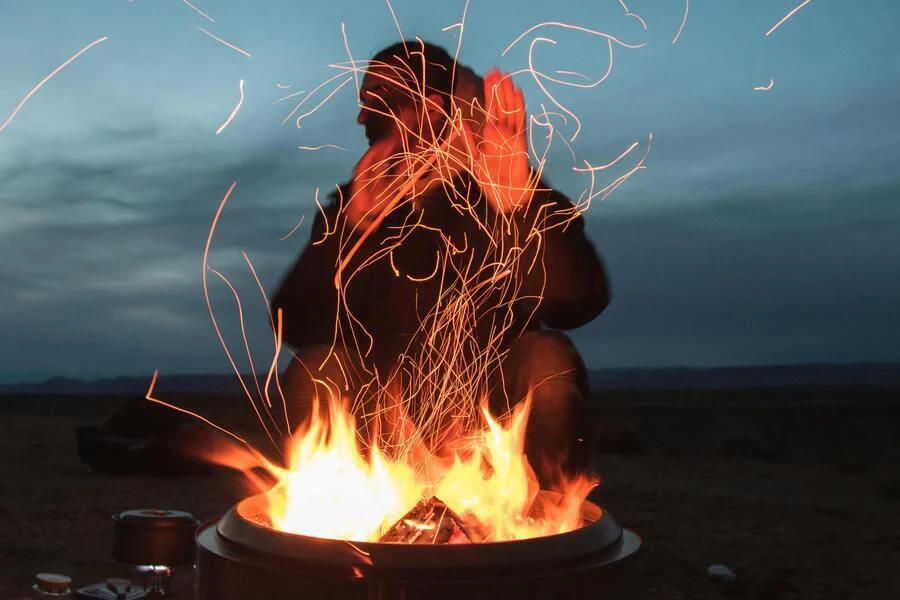 Man warming hands by a campfire