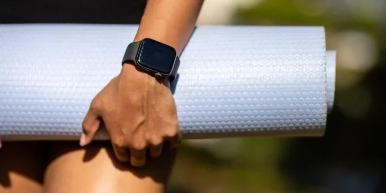 Человек с Apple Watch держит коврик для йоги