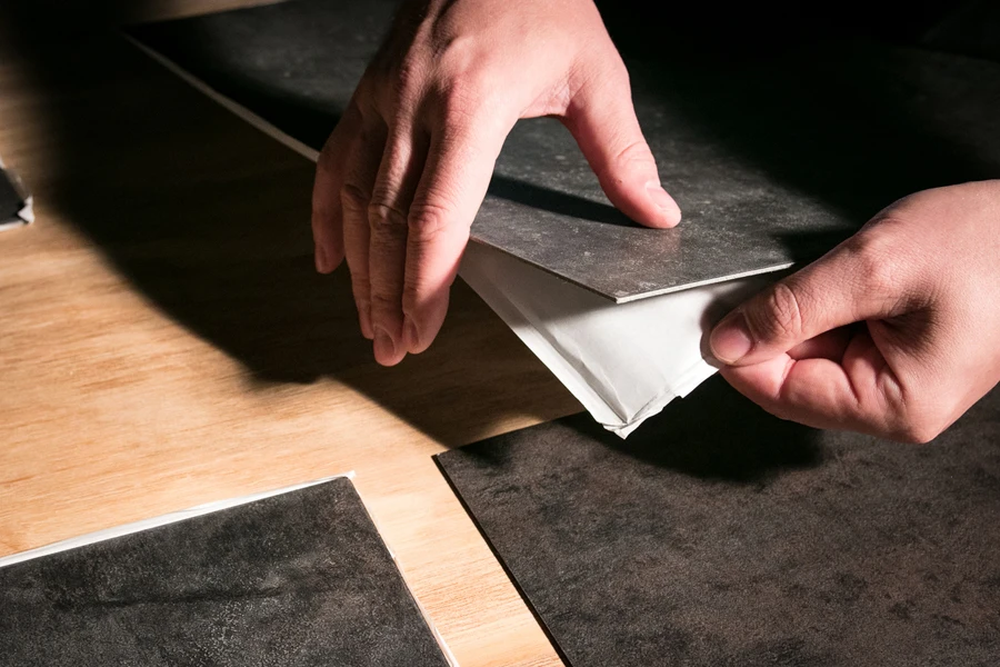 Person installing peel and stick floor tiles