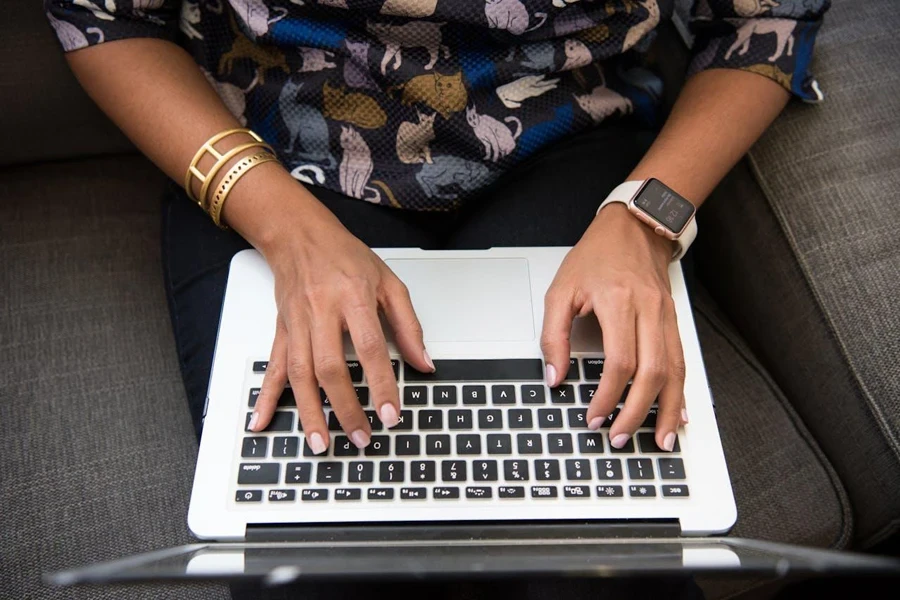 Person typing on a laptop wearing an Apple Watch