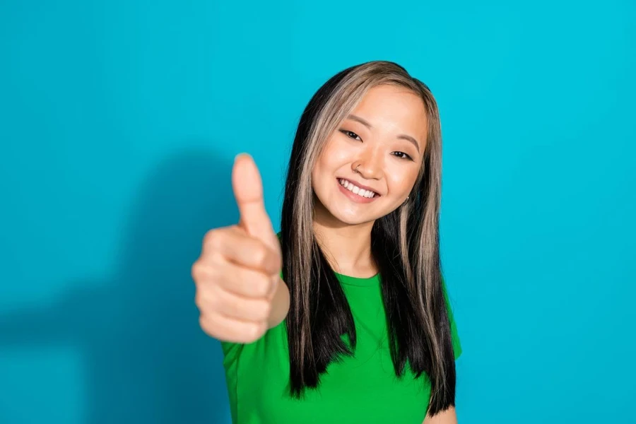 Photo of lovely young girl demonstrate thumb up wear t-shirt isolated on teal color background