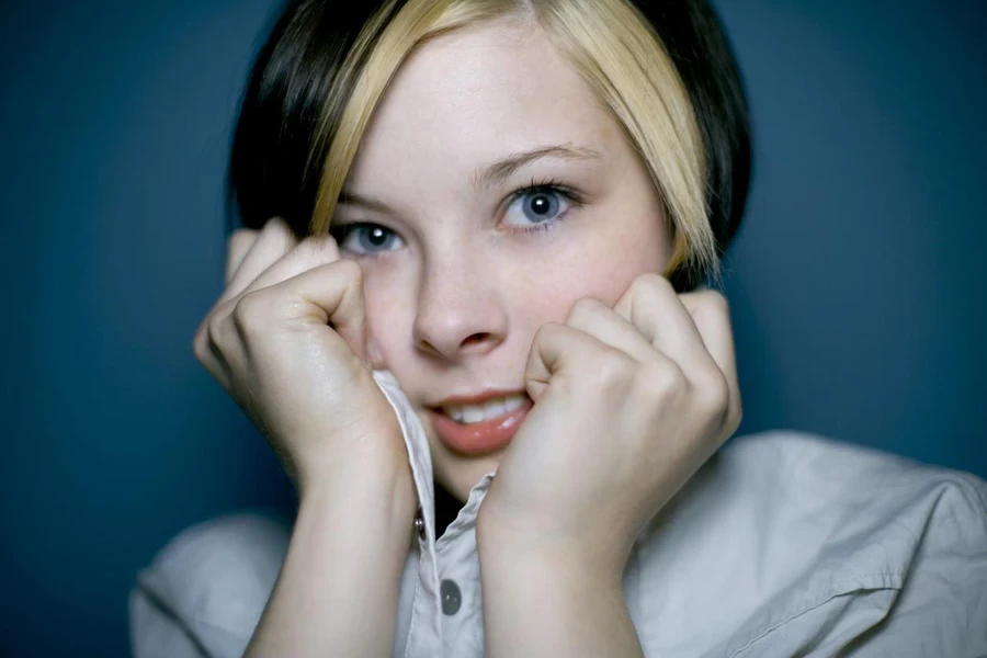 Pretty girl with short chunky highlights pulling on the collar.