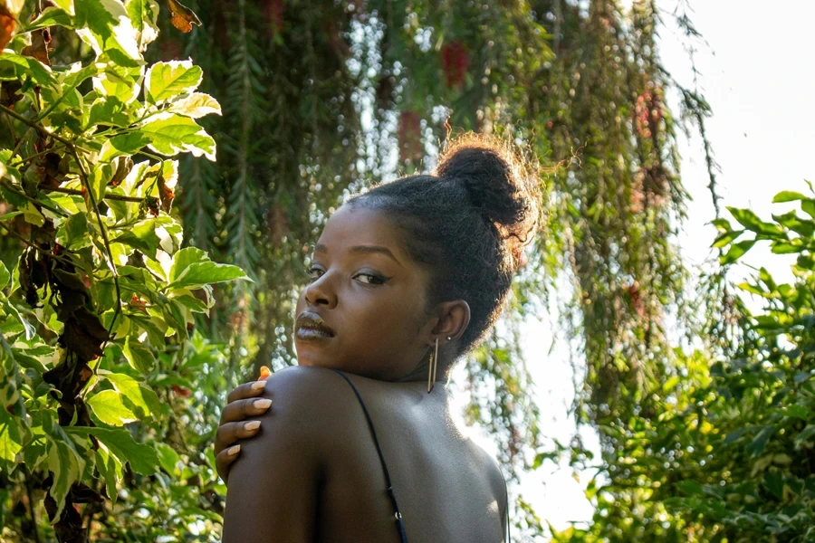 Topless girl standing next to leafy tree