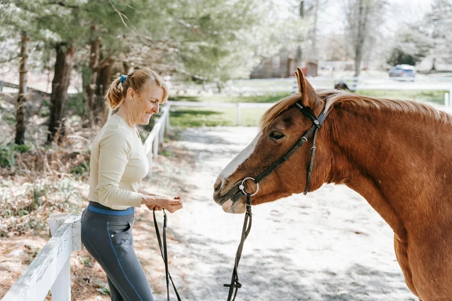 Woman Smiling While Feeding a Horse