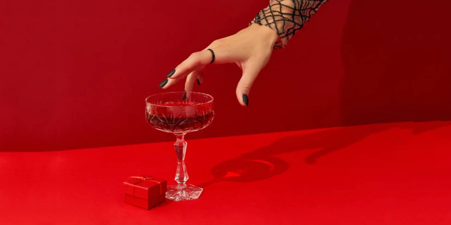 Woman Taking Glass with Cranberry Halloween Cocktail on Red Background