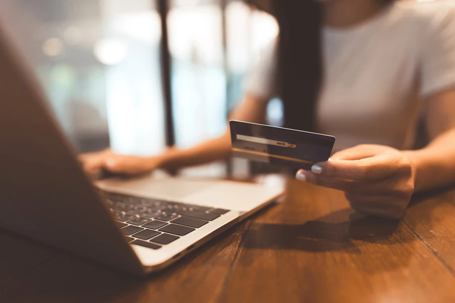 Woman holding a credit card while buying things on her laptop