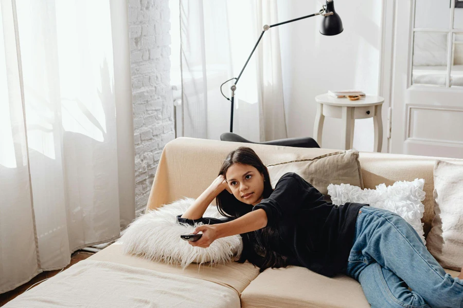 Woman in Black Shirt Lying on the Sofa Holding a Remote