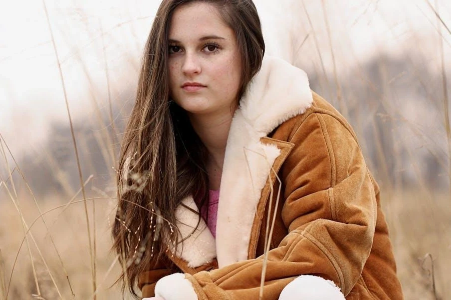 Woman posing in a brown, shearling-lined coat