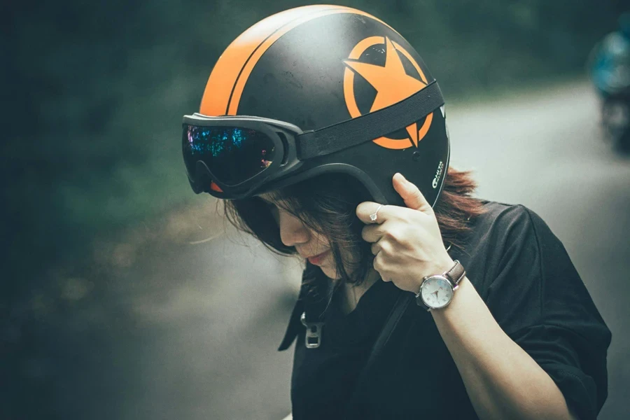 Woman wearing black shirt and black and orange half face helmet