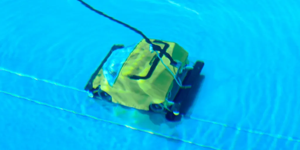 Yellow mechanical pool vacuum under swimming pool