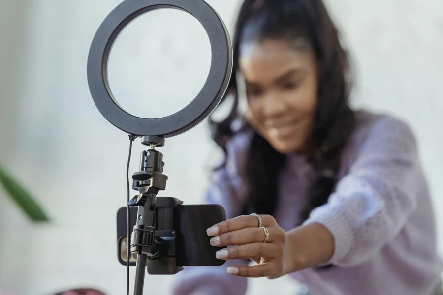 Young black woman setting up smartphone before shooting podcast