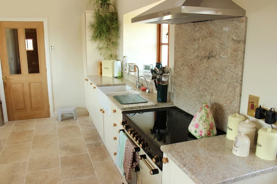 a kitchen with travertine backsplash and counter