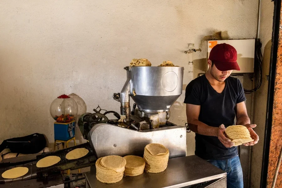 A man operating a tortilla machine