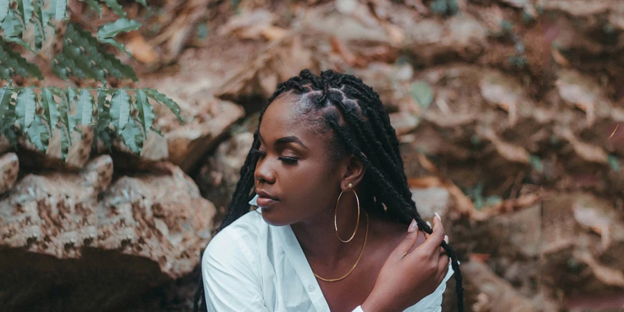 a woman with dreadlocks sitting in front of rocks