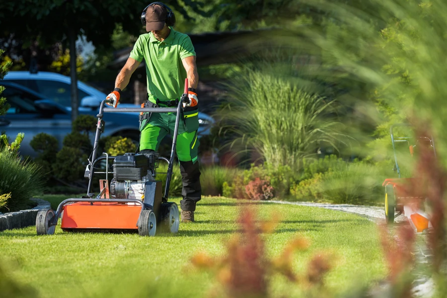 man using a petrol scarifier on a lawn