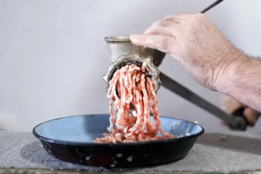 Person using a manual meat and bone grinder