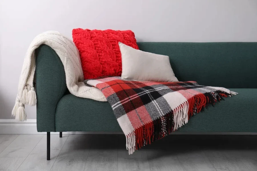 sofa with soft pillows and warm plaid blankets in a living room