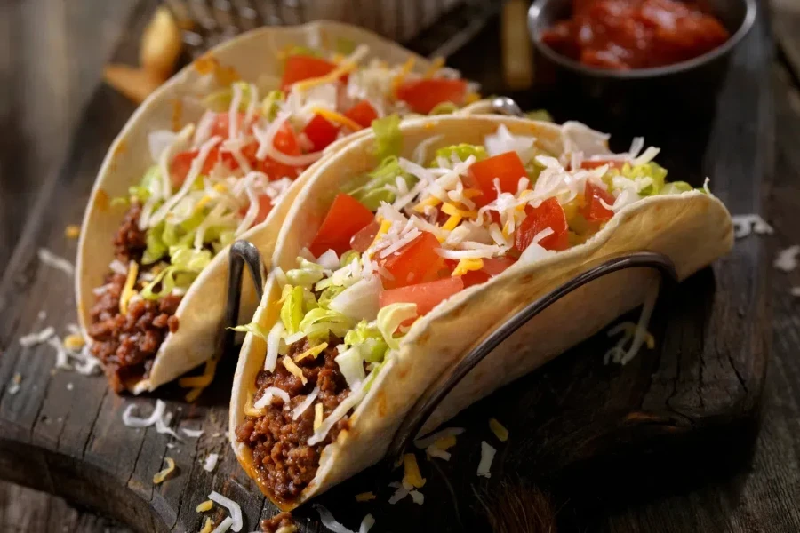 Soft tacos with ground beef, lettuce, tomato, onions and cheese