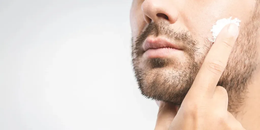 young man applying cream at his face