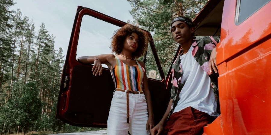 A Man and a Woman Leaning on Red Vehicle while Posing at the Camera