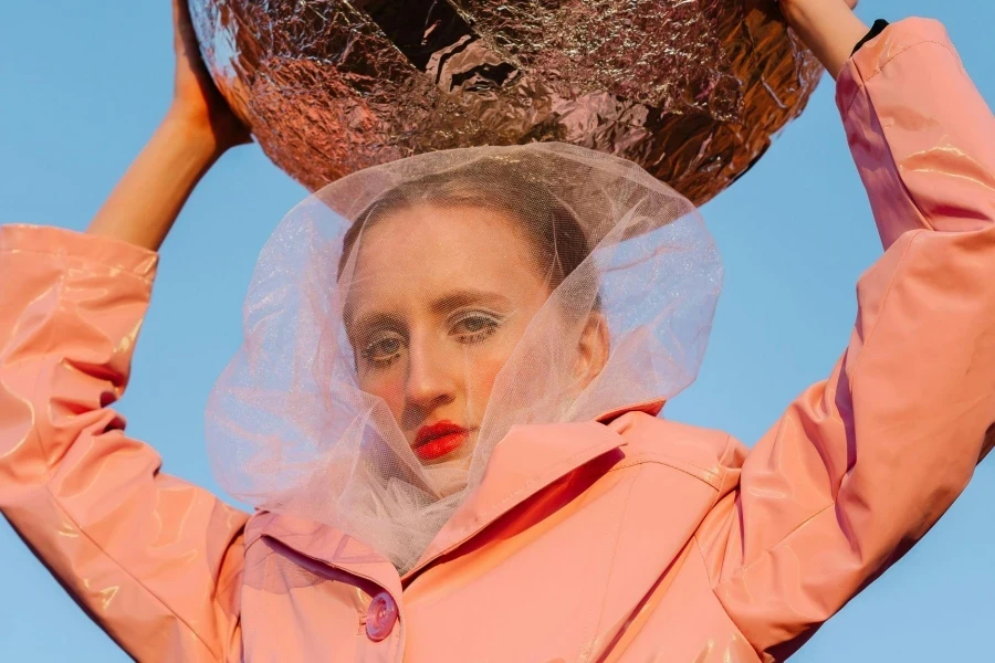 A Woman in a Pink Top Holding a Ball Covered with Foil