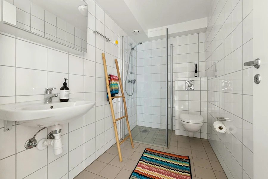 A bathroom with a rug, sink, toilet and shower