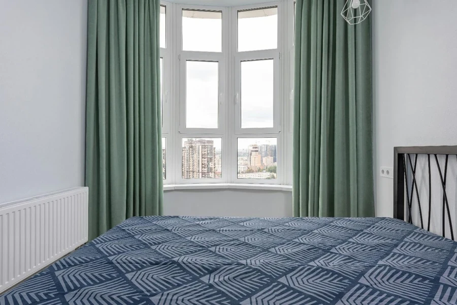 A bed with a blue blanket and green curtains