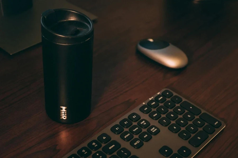 A black mug and keyboard on a desk