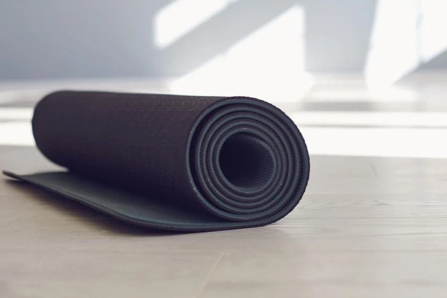 A black yoga mat on the floor in a bright sunny studio