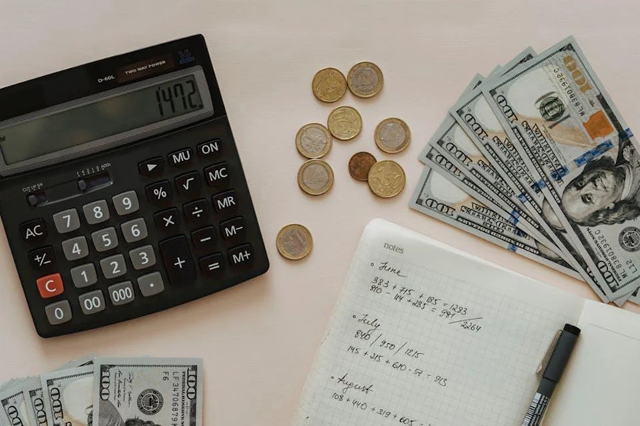 A calculator next to some dollar bills and coins