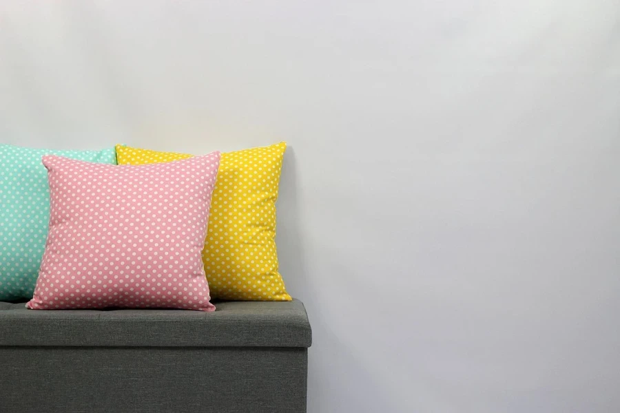 A group of colorful pillows on a grey bench