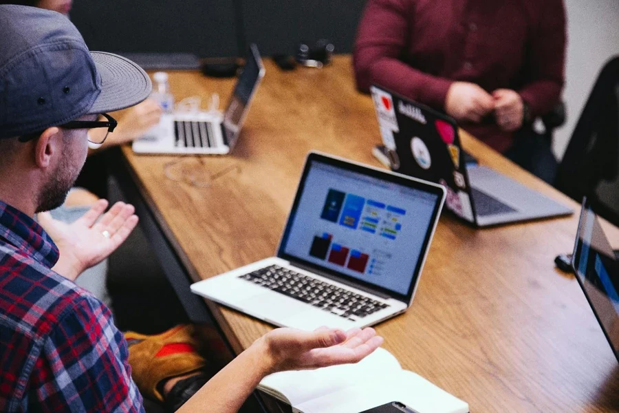 A group of people sitting at a table with laptops