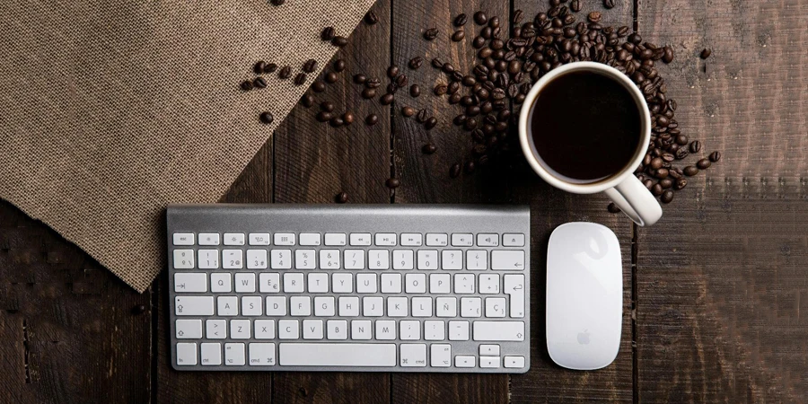 Una tastiera, un mouse e una tazza di caffè