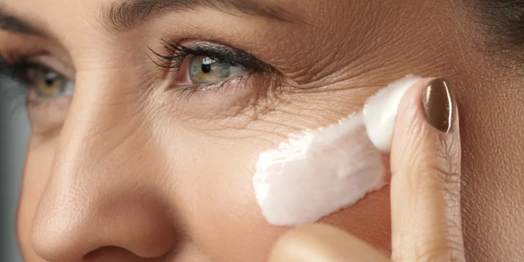 A middle-aged woman with fair skin tone applying anti-aging cream