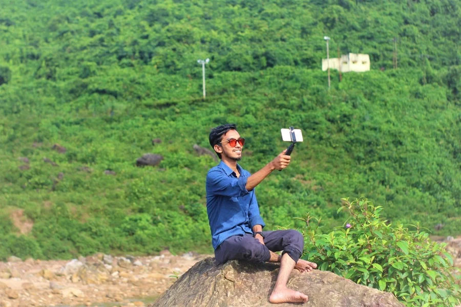 A person sitting on a rock taking a selfie